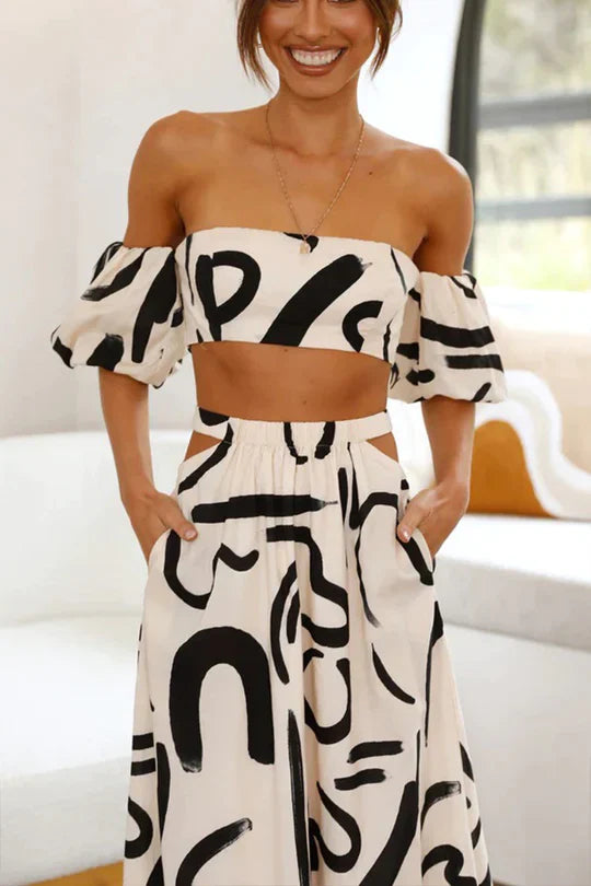 Ensemble assorti composé d'un top imprimé à épaules découvertes et d'une jupe longue avec découpes et poches, parfait pour un look d'été cool et à la mode.