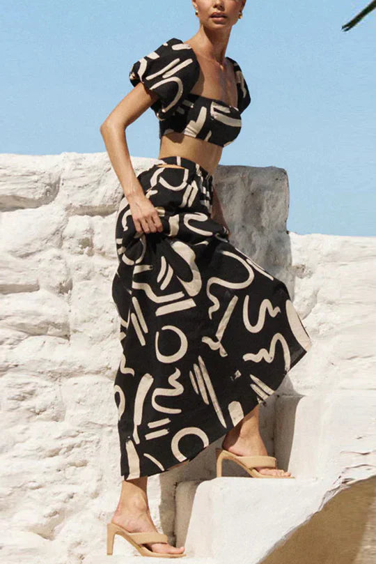 Ensemble assorti composé d'un top imprimé à épaules découvertes et d'une jupe longue avec découpes et poches, parfait pour un look d'été cool et à la mode.